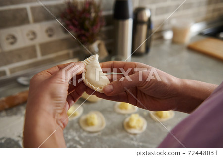 A woman making traditional dumplings ( vareniki or ravioli ) 72448031