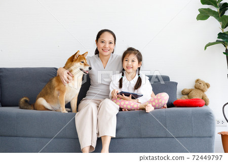 Happy Asian mother and daughter sitting on sofa in living room with their Shiba Inu. Concept family with dog at home. Happy Asian mother and daughter sitting on sofa in living room with their Shiba Inu. Concept family with dog at home. 72449797