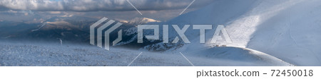 Snow covered mountain slope in last evening sunlight. Magnificent windy dusk on tops above picturesque alpine ski resort, Dragobrat, Ukraine, Carpathian Mountains. Snow covered mountain slope in last evening sunlight. Magnificent windy dusk on tops above picturesque alpine ski resort, Dragobrat, Ukraine, Carpathian Mountains. 72450018