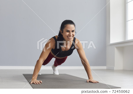 Attractive sports woman holding a plank and doing press exercises in a bright gym. Attractive sports woman holding a plank and doing press exercises in a bright gym. 72450062