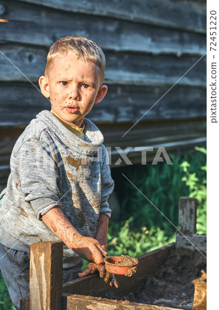 Funny dirty boy playing with toy cars in the sandbox 72451220