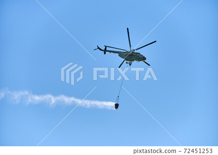 Fire fighting helicopter with water bucket on blue sky background Fire fighting helicopter with water bucket on blue sky background 72451253