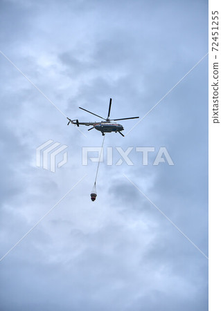 Fire fighting helicopter with water bucket on a gloomy sky background 72451255