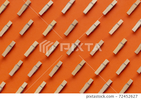 Many wooden clothespin on orange background. Many wooden clothespin on orange background. 72452627