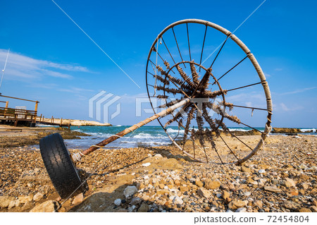 Abandoned beach umbrella on a rocky beach set against the sea. Abandoned beach umbrella on a rocky beach set against the sea. 72454804