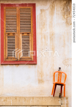 Orange chair hanging on the wall and beautiful wooden window of a traditional house in the old city of Nicosia, Cyprus Orange chair hanging on the wall and beautiful wooden window of a traditional house in the old city of Nicosia, Cyprus 72454810
