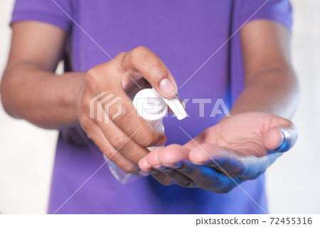 young man hand using sanitizer gel for preventing virus on white background  72455316