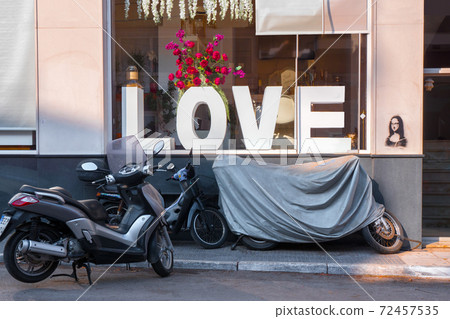 Motorbikes near LOVE word on shop window. Sign and symbol of love. Conceptual photo. Love theme. Rock style background. Big letters LOVE and motorbikes, motorcycle outdoor near the window shop Motorbikes near LOVE word on shop window. Sign and symbol of love. Conceptual photo. Love theme. Rock style background. Big letters LOVE and motorbikes, motorcycle outdoor near the window shop 72457535