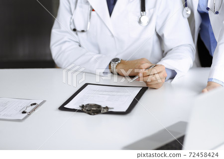 Group of unknown doctors are sitting at the desk and discussing problems or disease treatment in modern hospital office. Coronavirus countering, patient help in medicine concept 72458424