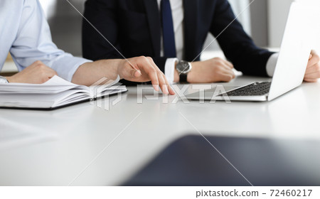 Unknown business people using laptop computer at the desk in modern office. Businessman or male entrepreneur is working with his colleague. Teamwork and partnership concept Unknown business people using laptop computer at the desk in modern office. Businessman or male entrepreneur is working with his colleague. Teamwork and partnership concept 72460217
