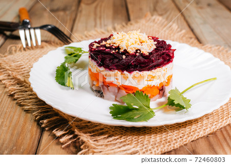 Traditional Russian herring under a fur coat in transparent plate with parsley. Rustic style. Traditional Russian herring under a fur coat in transparent plate with parsley. Rustic style. 72460803