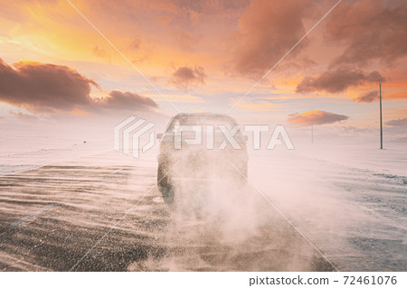 Snow-covered Open Slippy Road During A Snowstorm Blizzard In Winter. Altered Colorful Sunset Sunrise Sky. Car In Dangerous Motion Snow-covered Open Slippy Road During A Snowstorm Blizzard In Winter. Altered Colorful Sunset Sunrise Sky. Car In Dangerous Motion 72461076