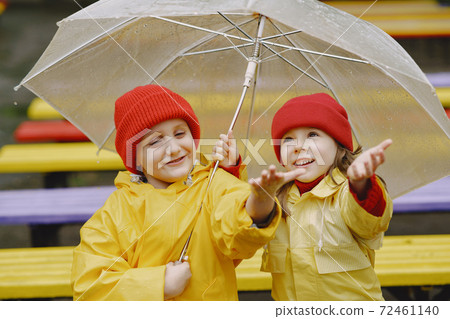 Funny kids in rain boots playing in a rainy park 72461140