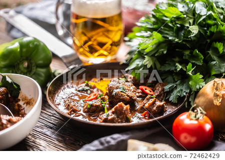 Goulash served in a pan with a fresh tap beer in the background Goulash served in a pan with a fresh tap beer in the background 72462429