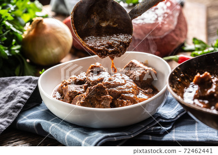 Cooked beef for a meat stew with sauce poured over it bz a ladle Cooked beef for a meat stew with sauce poured over it bz a ladle 72462441