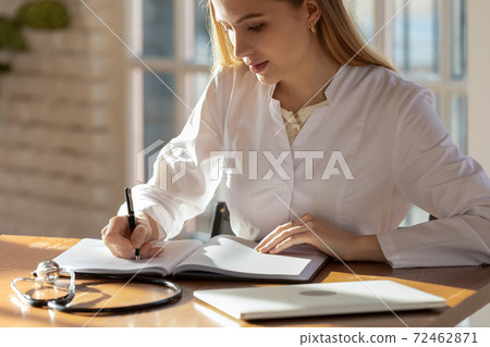 Female nurse write in medical journal in hospital 72462871