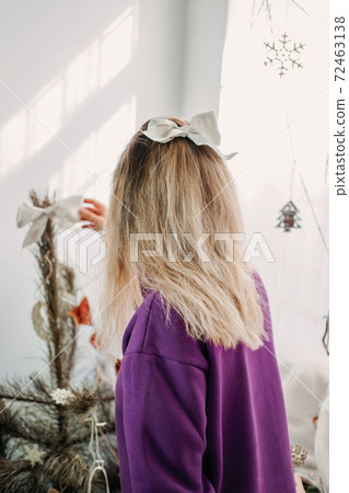 Holiday christmas decorating at home. Young woman putting ornaments on xmas tree, setting up lights. Budget hristmas Home Decor Ideas Holiday christmas decorating at home. Young woman putting ornaments on xmas tree, setting up lights. Budget hristmas Home Decor Ideas 72463138
