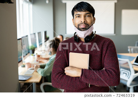 Young bearded mixed-race male with notebook in hands and headset on neck 72463319