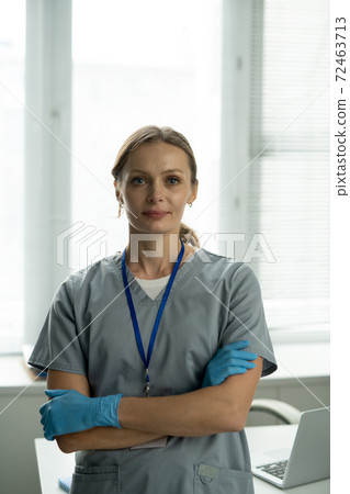 Successful clinician in uniform and protective gloves crossing arms by chest Successful clinician in uniform and protective gloves crossing arms by chest 72463713