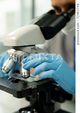 Gloved hand of scientific laboratory worker or researcher fixing metallic lens Gloved hand of scientific laboratory worker or researcher fixing metallic lens 72463749