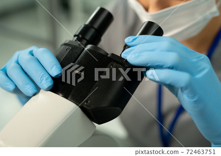 Gloved hands of worker of scientific laboratory investigating chemical sample Gloved hands of worker of scientific laboratory investigating chemical sample 72463751