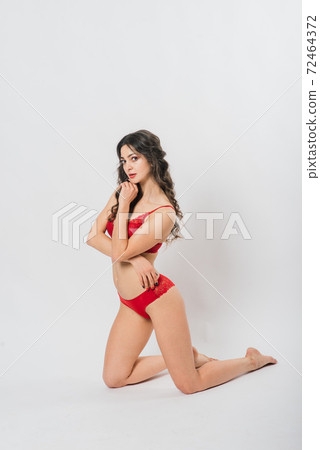 Cute brunette female model posing, wearing black and red underwear in white studio 72464372