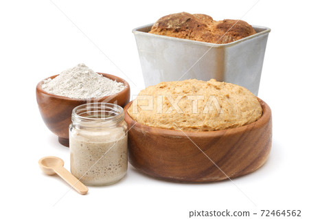 Natural leaven for bread in a glass jar, wooden bowl of dough, bowl of flour and freshly baked loaf in baking tin on white. Natural leaven for bread in a glass jar, wooden bowl of dough, bowl of flour and freshly baked loaf in baking tin on white. 72464562