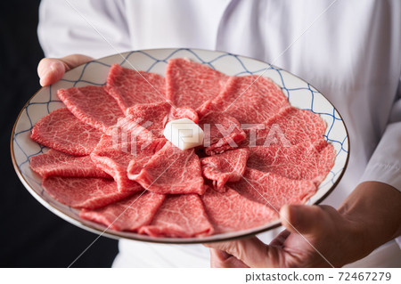 Itamae holding a beef shoulder loin slice in hand Itamae holding a beef shoulder loin slice in hand 72467279