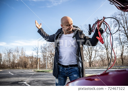 Angry driver trying to start broken car with jumper cables 72467322
