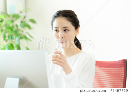 Young woman hydrating in the office Young woman hydrating in the office 72467759
