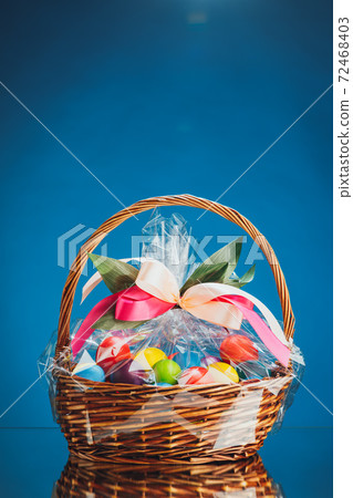 Easter gift basket with multicolor eggs, blue background 72468403