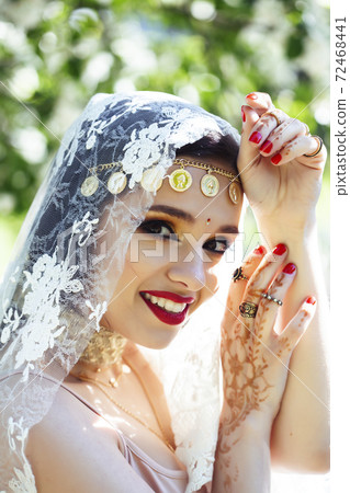 young pretty indian girl in jewelry and veil posing cheerful happy smiling in green park, lifestyle people concept 72468441