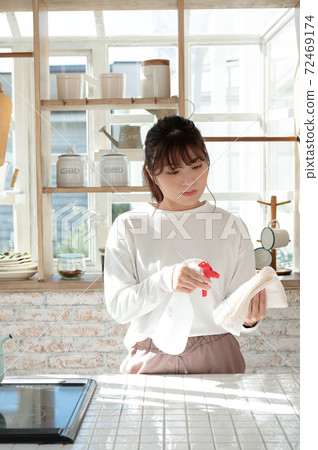 一名年輕女子用抹布和消毒劑噴霧清洗廚房 72469174
