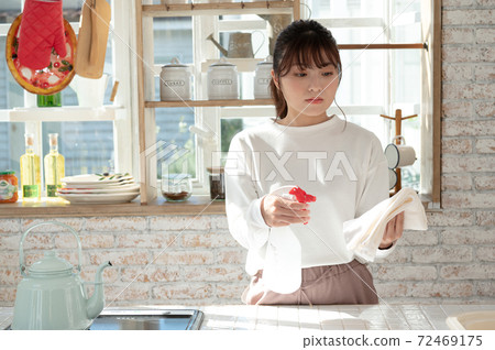 一名年輕女子用抹布和消毒劑噴霧清洗廚房 72469175