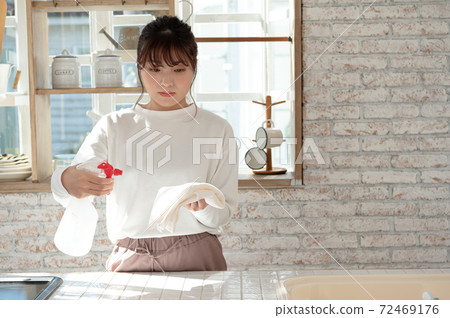 一名年輕女子用抹布和消毒劑噴霧清洗廚房 一名年輕女子用抹布和消毒劑噴霧清洗廚房 72469176