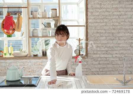 一名年輕女子用抹布和消毒劑噴霧清洗廚房 72469178