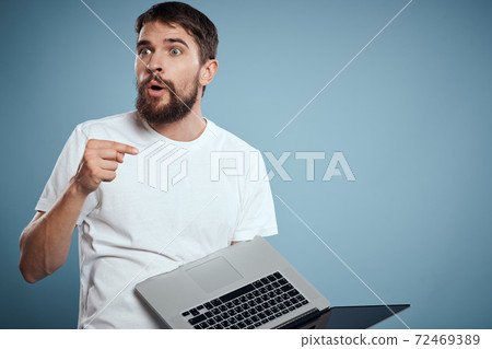 Emotional man with laptop in hands on blue background monitor keyboard internet model cropped view Emotional man with laptop in hands on blue background monitor keyboard internet model cropped view 72469389