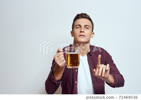 Drunk man with a mug of beer vacation alcohol lifestyle in a red shirt emotions light background 72469536