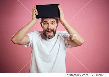 Man advertises a tablet on a pink background codes Space cropped view of emotions white t-shirt model new technologies 72469630