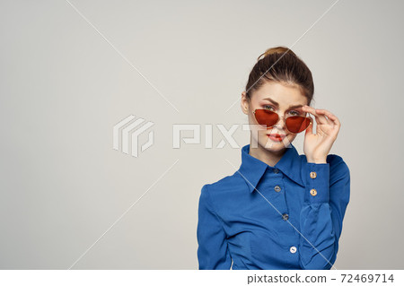 Portrait of a woman in sunglasses and a blue shirt on a light background cropped view of Model Copy Space Portrait of a woman in sunglasses and a blue shirt on a light background cropped view of Model Copy Space 72469714