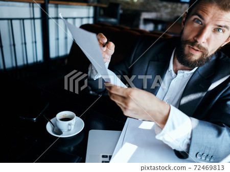 Business man in a cafe suit in front of laptop emotions official documents technology 72469813