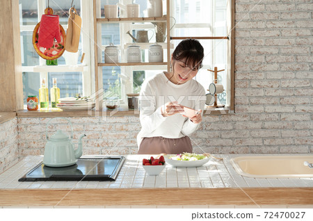 A young woman taking a picture of her salad with her smartphone 72470027