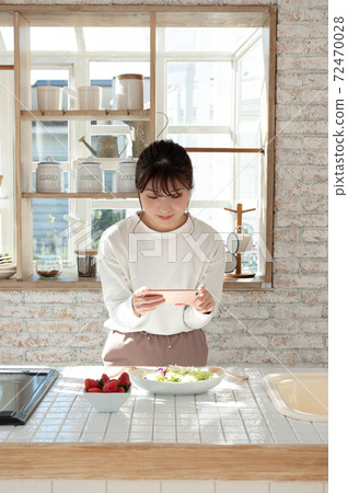 A young woman taking a picture of her salad with her smartphone 72470028