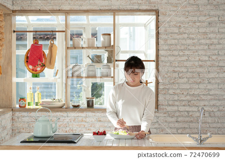 Young woman serving salad in the kitchen 72470699