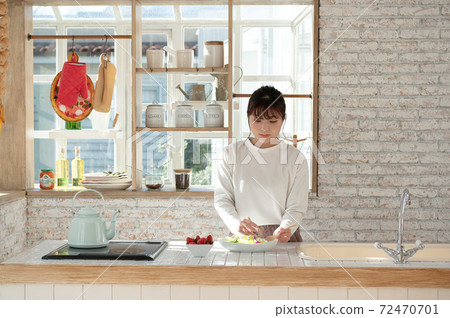 Young woman serving salad in the kitchen Young woman serving salad in the kitchen 72470701