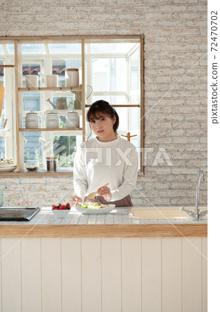 Young woman serving salad in the kitchen Young woman serving salad in the kitchen 72470702