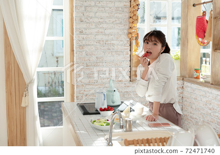 一個年輕的女人,做完飯,撿起吃草莓 一個年輕的女人,做完飯,撿起吃草莓 72471740
