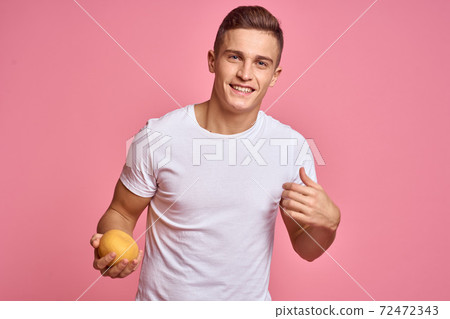 Man with fruits in hands on a pink background healthy food vitamins pink background white t-shirt model Man with fruits in hands on a pink background healthy food vitamins pink background white t-shirt model 72472343