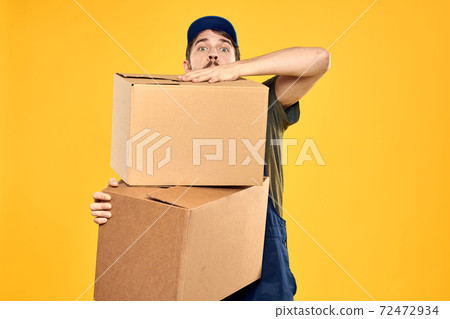 A man in a working form a box with loading tools yellow background 72472934