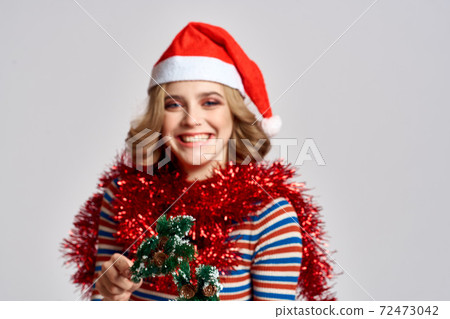 emotional woman with branches of a festive tree and red tinsel cap on her head striped sweate 72473042